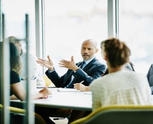 A man and woman sitting at a table talking to each other.