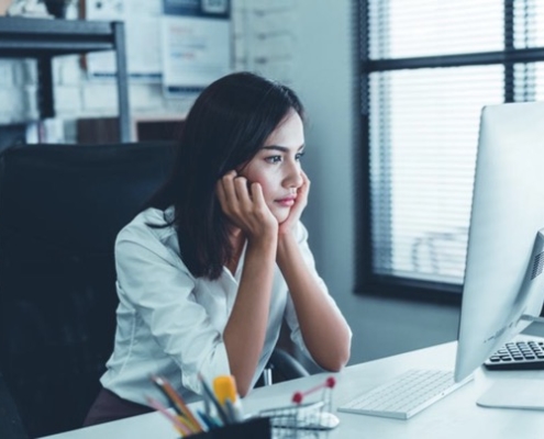 A woman sitting at her desk looking at the computer.