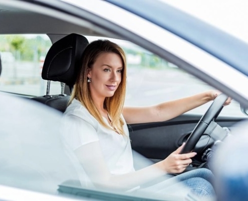 A woman sitting in her car driving.