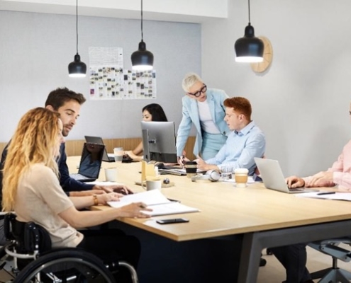 A group of people sitting at a table with laptops.