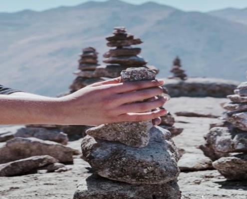 A person is holding their hands over rocks.