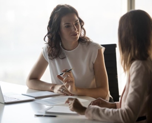 Two women sitting at a table talking to each other.