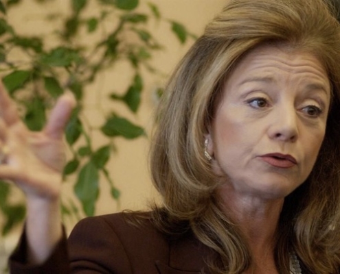 A woman with long hair and a brown jacket