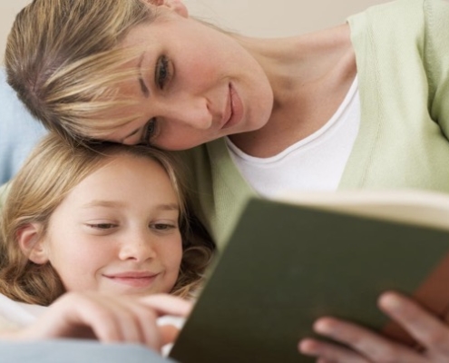 A woman and girl reading a book together.