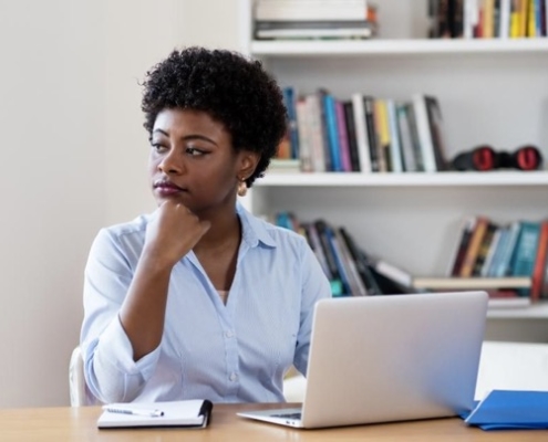 A woman sitting at a table with her laptop.