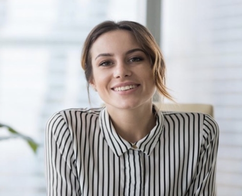 A woman sitting in an office chair smiling for the camera.