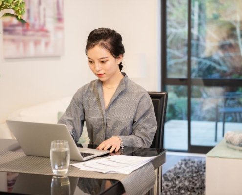 A woman sitting at a table using her laptop.