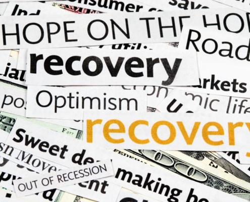 A pile of newspaper headlines with words that say recovery, optimism and recover.