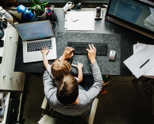 A man sitting at his desk with two laptops.