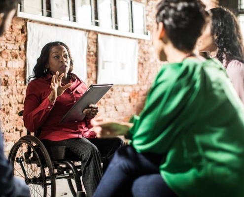 Two women are sitting in a room talking to each other.