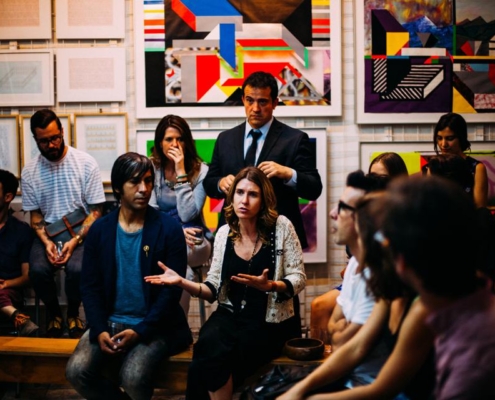 A group of people sitting around in front of some paintings.