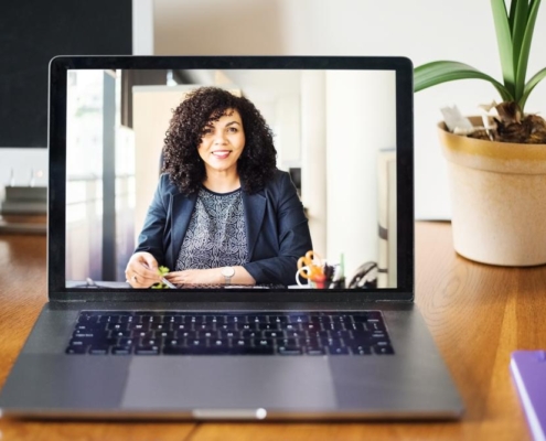 A laptop with a woman on the screen.