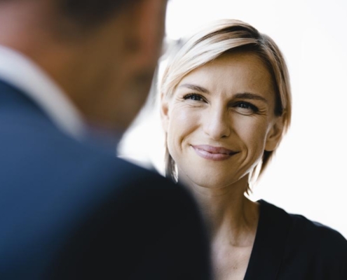 A woman smiles at the camera while another man looks on.