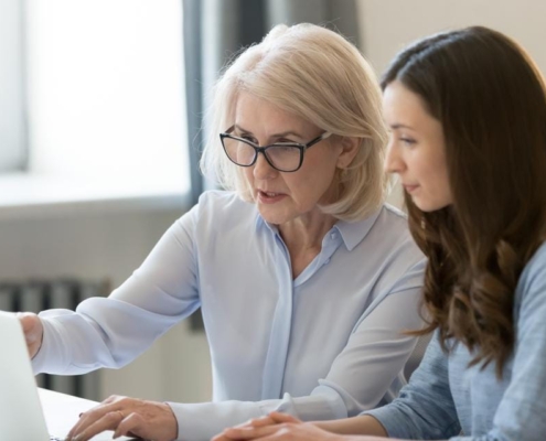 A woman and her daughter looking at something on the computer.