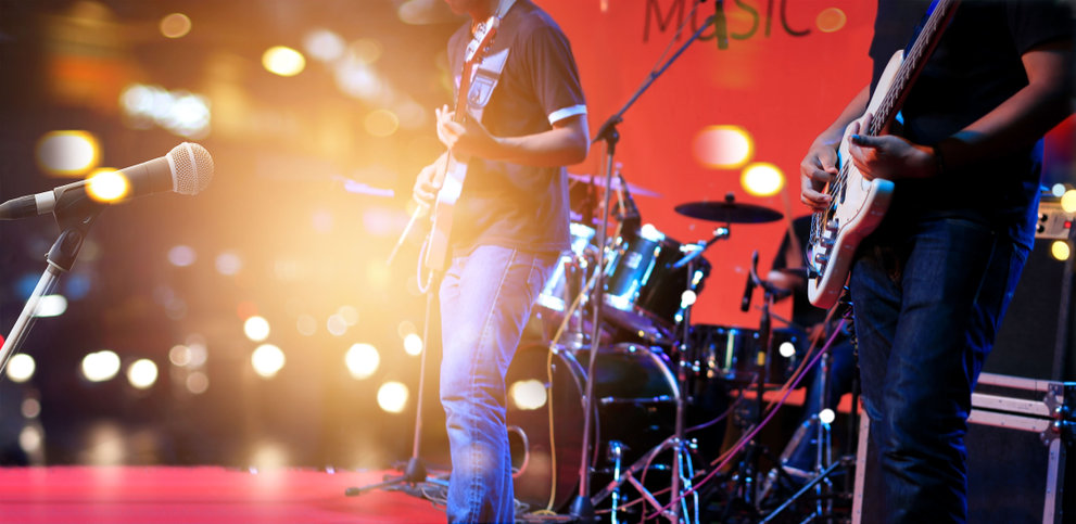 A man playing guitar on stage with drums.